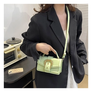 Close-up of mint green handbag featuring a vintage gold buckle and textured leather finish