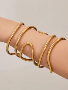 Dettaglio del bracciale a doppia spirale placcato in oro minimalista sul braccio di una modella