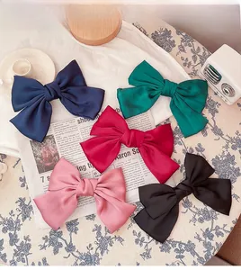 Macro detail of oversized satin bow hair clips in navy, green, rose, pink and black