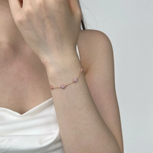 Detail of rose gold clover bracelet with pink pave zircon charms on female wrist