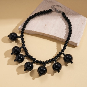 Detail of chunky black acrylic beads with silver lobster clasp on a beige stone