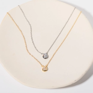 Detailed close-up of gold and silver necklaces with pear-shaped gemstone pendants