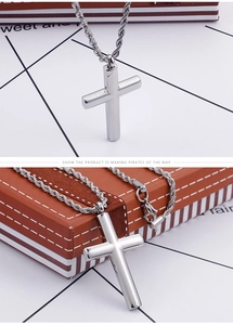 Close-up of a polished silver cross pendant with a thick twist chain on a gift box