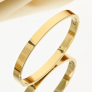 Macro shot of minimalist gold stainless steel bangle with polished finish and snap closure