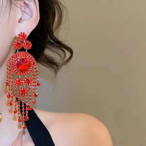 Close-up of elegant red crystal tassel earrings with sparkling rhinestones on model