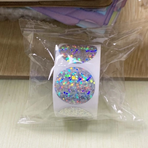Macro shot of silver holographic circular roll labels on a rustic wooden surface
