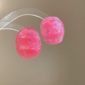 Macro shot of pink oval earrings featuring a horizontal brushed texture on resin surface