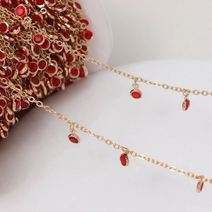 Macro detail of gold plated jewelry chain with red round crystal pendants for DIY crafts