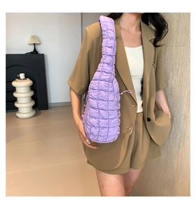 Détail du sac nuage matelassé violet avec poignée à cordon porté à l'épaule sur blazer
