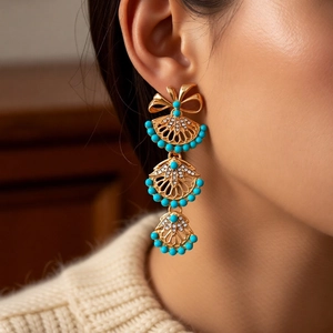 Détail macro de boucles d'oreilles vintage en éventail avec perles turquoise et doré
