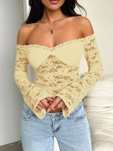 Détail du tissu en dentelle beige sur un haut à manches longues et épaules dénudées