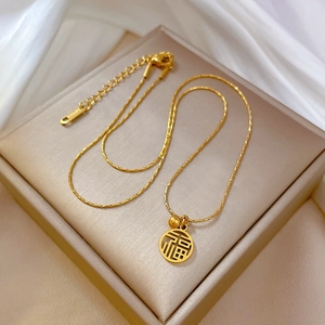 Détail du pendentif doré Fu avec gravure K18 sur un collier minimaliste en acier