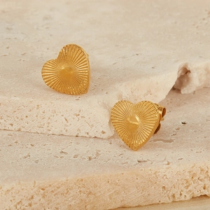 Macro shot of gold-plated heart stud earrings with radial sunburst texture on stone