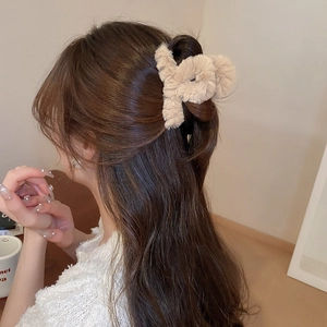 Detail of plush rabbit hair claw clip in beige on model's hair for autumn winter style