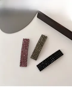 Detailed macro view of rectangular hair clips with pavé-set rhinestones in purple, green, and black