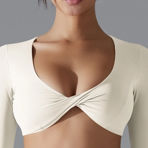 Dettaglio del nodo incrociato sul crop top da yoga a maniche lunghe bianco panna