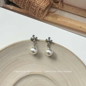 Gros plan de boucles d'oreilles croix en argent et perles sur un plateau en céramique