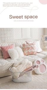 Detail of pink velvet and white plush cat paw cushions arranged on a modern sofa