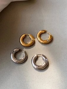 Polished gold and silver hoop earrings with embedded zircon stones on grey background