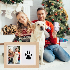 Cornice in legno chiaro con impronta di zampa e foto di famiglia in un ambiente natalizio