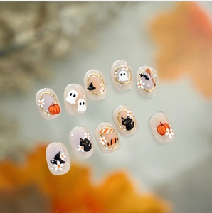 Macro shot of 3D Halloween nail charms with gold borders featuring ghosts and pumpkins