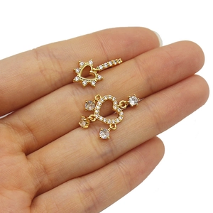 Detailed close-up of small golden heart pendant earrings with sparkling white crystals