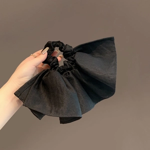 Elegant oversized black fabric scrunchie with ruffled texture held by a person
