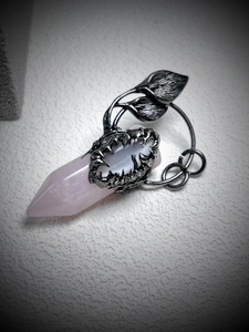 Macro shot of rose quartz crystal pendant in retro silver monster-shaped setting