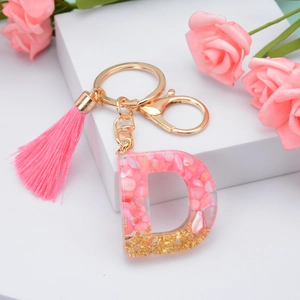 Pink resin letter D keychain with gold leaf, pink tassel and floral background decoration