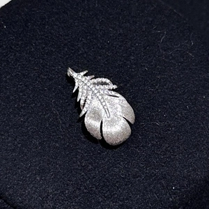 Detailed close-up of feather-shaped brooch with silver plating and white zircon inlay