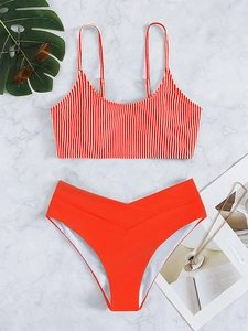 Red and white striped bikini top with high-waisted red bottoms on marble background