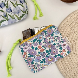 Close-up of floral makeup bag with yellow zipper, neon green rope, and cosmetics