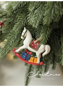 Detail of hand-painted resin rocking horse Christmas ornament with gift boxes on tree
