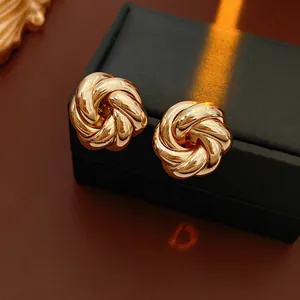Polished gold spiral woven earrings displayed on a dark luxury jewelry gift box