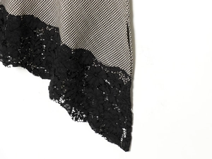 Close-up of houndstooth fabric with intricate black floral lace trim detailing