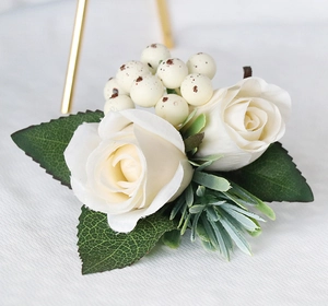 Detail of handmade cream rose boutonniere with green leaves and berries for wedding