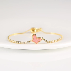 Detailed shot of a gold butterfly bracelet with pink charm and white zircon stones