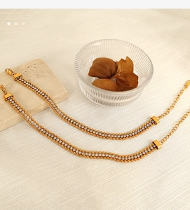 Close-up of gold chain bracelets with dense rows of cubic zirconia on beige fabric