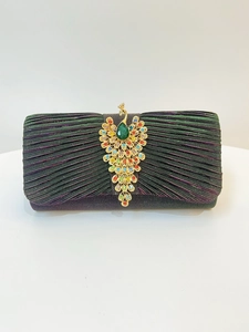 Macro view of pleated fabric and elegant golden peacock brooch with green gemstone