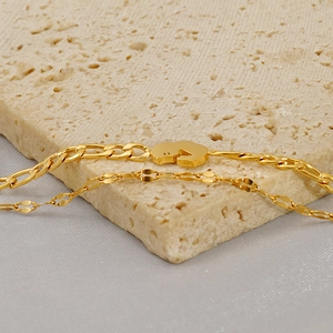 Detailed macro view of dual-layer gold anklet with Figaro chain and abstract pendant charm
