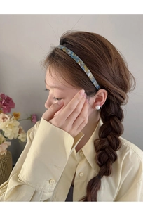Détail d'un serre-tête en acétate à fleurs bleues porté pour une coiffure d'été