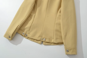 Detail of yellow jacket back hem featuring adjustable snap waist tabs and metal zipper