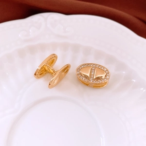 Detail of 18K gold-plated oval anchor earrings with zircon inlay on white ceramic plate
