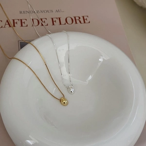 Macro view of minimalist 925 sterling silver oval bean necklaces in gold and silver finish