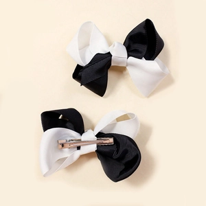 Detail view of black and white grosgrain hair bow clips showing the metal duckbill clamp