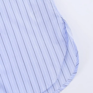 Detail shot of light blue striped shirt featuring a curved hem and fine woven texture