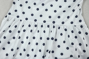 Detailed view of white polka dot dress with elastic waist stitching and fabric texture