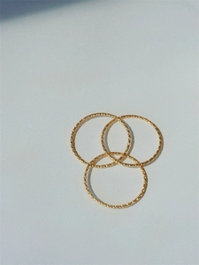 Detailed view of three minimalist gold-toned rings with textured diamond-cut surface