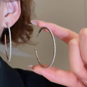 Close-up of sparkling crystal encrusted silver hoop earrings worn by a model