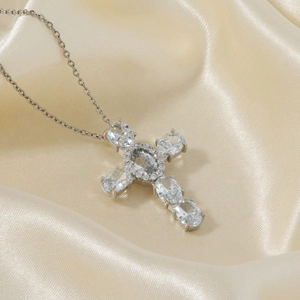 Silver cross pendant necklace with micro-pave zircons on elegant beige satin fabric